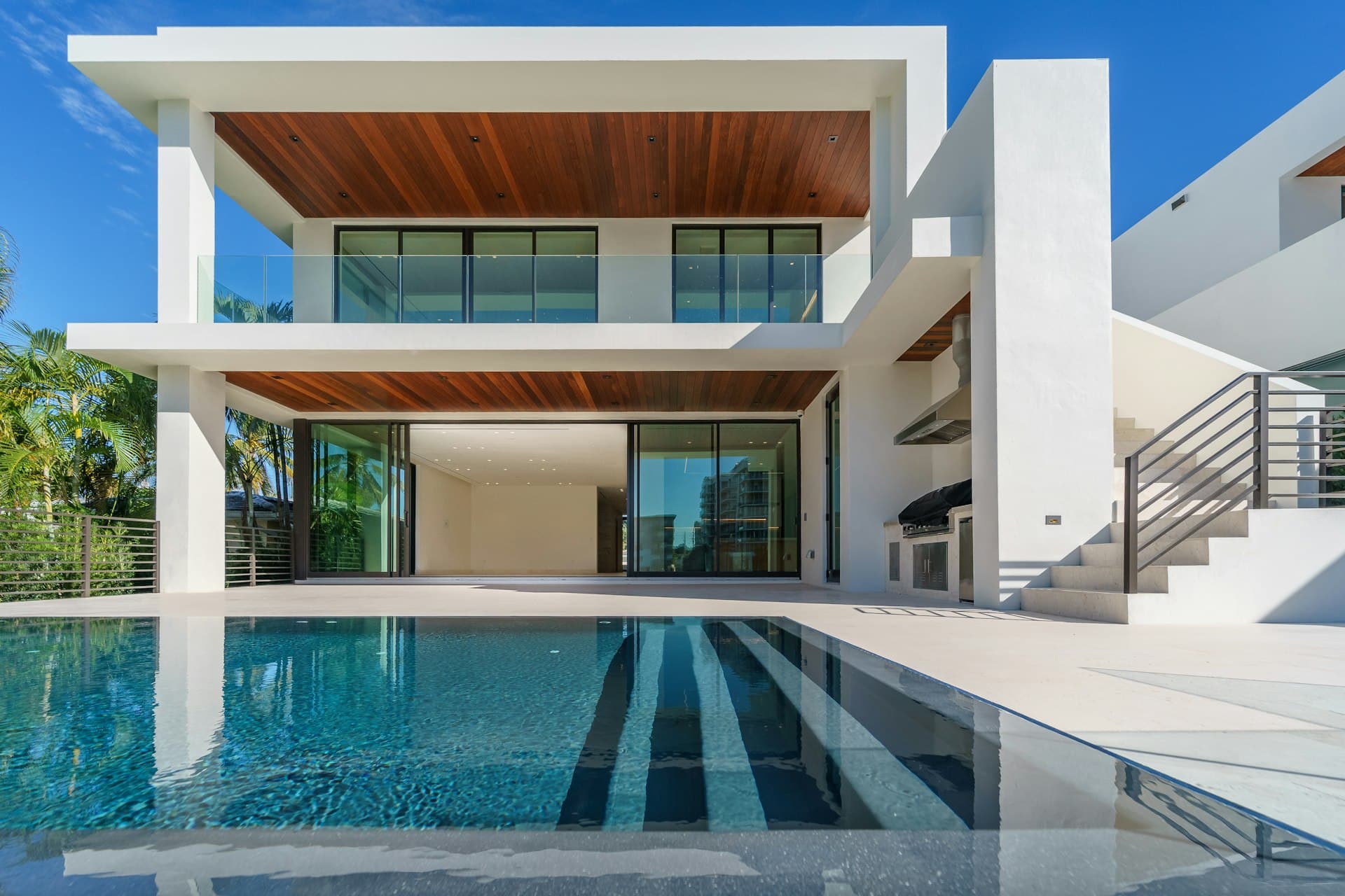 Villa contemporaine avec piscine à débordement, grandes baies vitrées et plafond bois, éclairée à la tombée du jour